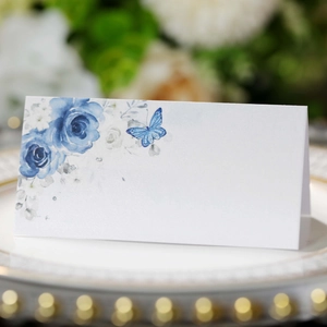 Detail of floral butterfly place card with blue roses on elegant dinnerware