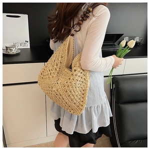 Detail of straw woven tote with dark brown wooden bead shoulder strap on a model