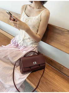 Detail of burgundy leather square handbag with silver metallic lock and top handle