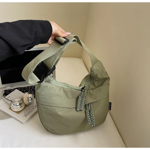 Detail of green nylon dumpling bag with adjustable strap and side brand label