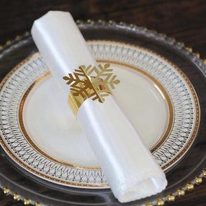 Detail of a golden snowflake napkin ring with intricate cutouts on a holiday table