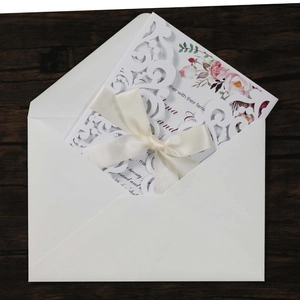 Détail d'invitation de mariage découpée au laser avec nœud en soie blanche