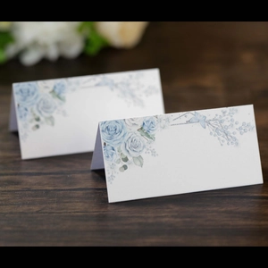 Close-up of white wedding place cards with elegant light blue watercolor rose floral prints