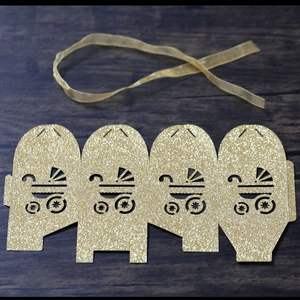 Detail of laser-cut glitter gold baby stroller candy box with matching silk ribbon