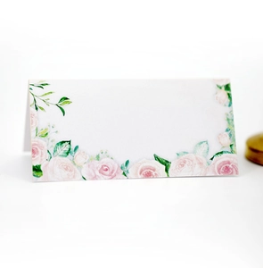 Détail d'un marque-place blanc élégant avec imprimé floral rose et texture papier