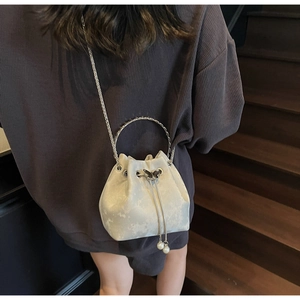 Detail of light beige satin bucket bag with pearl drawstring and silver chain strap