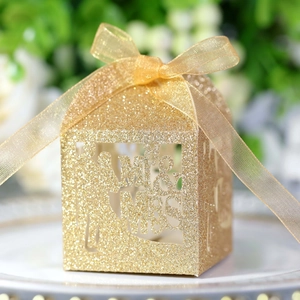 Detailed laser-cut Mr & Mrs lettering on a gold glitter wedding favor candy box with ribbon