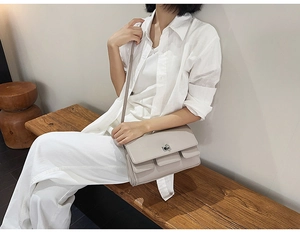 Detail shot of grey faux leather handbag with silver twist lock and minimalist stitching