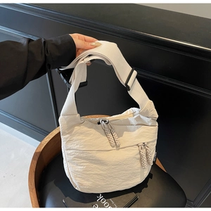 Detailed shot of off-white nylon crossbody bag featuring textured fabric and rope zipper
