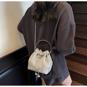Detail of silver velvet bucket bag with rhinestone ring handle and pearl drawstring charms