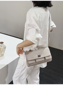 Detail of light gray crossbody bag featuring elegant silver twist lock and minimalist design