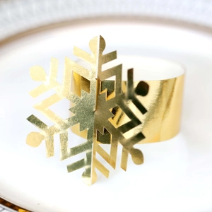 Close-up of a polished gold snowflake napkin ring on a white decorative plate
