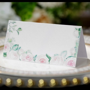 Marque-place de mariage élégant avec roses roses posé sur une assiette dorée
