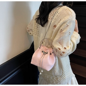 Detail of pink velvet drawstring bucket bag with large pearl charm and silver chain strap