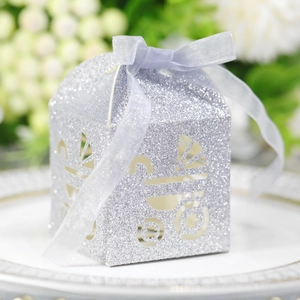 Silver glitter gift box with baby stroller cutout and blue ribbon on white plate