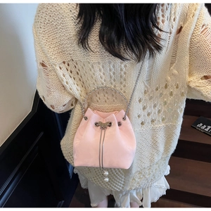 Detail of pink velvet bucket bag featuring pearl charms and silver chain strap