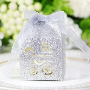 Close-up of silver glitter hollow stroller candy box with purple ribbon on a dinner plate