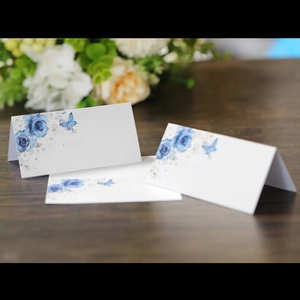 Elegant white wedding place card with blue floral roses and butterfly on wood
