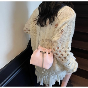 Detail of pink drawstring bucket bag with metal butterfly buckle and pearl charms