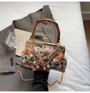 Detail of crochet bear bag featuring bamboo handle, pearl chain and floral embroidery
