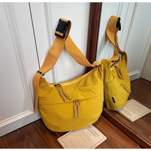 Detailed close-up of a yellow nylon crossbody bag featuring a wide strap and plastic buckle