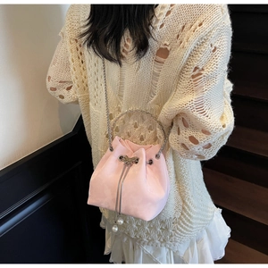 Detail of pink drawstring bucket bag featuring a metal butterfly buckle and pearl pendant