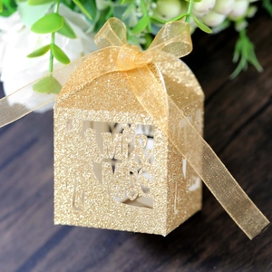 Macro detail of Mr & Mrs hollow out gold glitter wedding candy box with silk ribbon bow