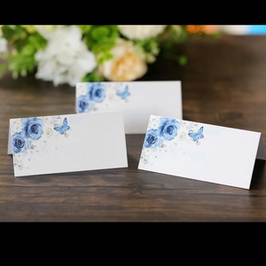 Detail of folded wedding place cards with blue roses and butterfly watercolor prints
