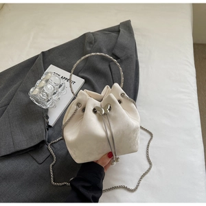 Detail of cream suede bucket bag featuring silver circular handle and butterfly drawstring lock