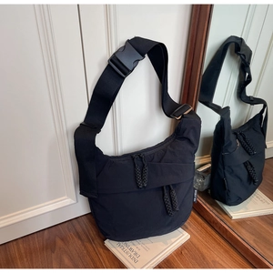 Detail of black nylon crescent crossbody bag featuring multiple zippers and wide strap