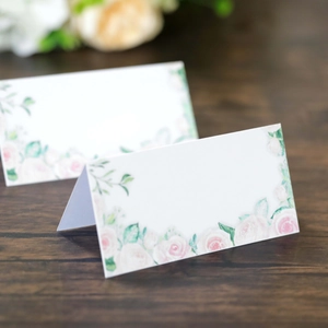 Cartes de table de mariage blanches avec imprimé rose rose sur fond bois foncé