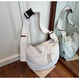 Close-up of cream crossbody bag featuring crinkled fabric and wide adjustable strap