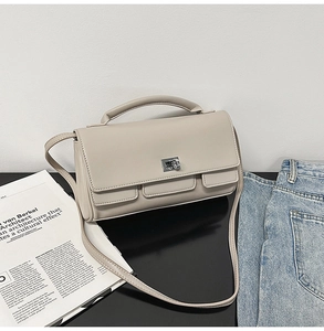 Detailed close-up of beige square handbag showing silver buckle and matte leather texture
