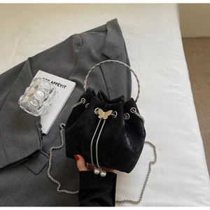 Detail of black velvet bucket bag featuring silver butterfly charms and pearl drawstring