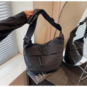 Detail of black nylon messenger bag with woven zipper pull and adjustable strap