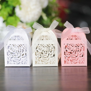 Detail of laser-cut rose hollow candy boxes in white, cream, and pink with ribbon bows