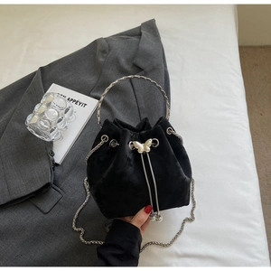 Detail of black velvet bucket bag featuring silver butterfly clasp and metal ring handle