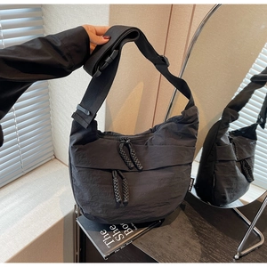 Detail of black nylon crossbody bag with adjustable wide strap and decorative zipper pull