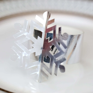 Macro shot of a silver snowflake napkin ring on white plate for Christmas table decor