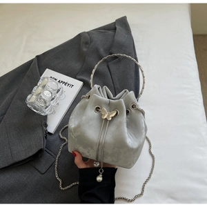 Detail of grey bucket bag with silver butterfly charm, pearl tassels and chain strap