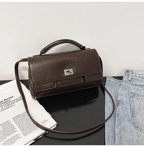 Detail of dark brown leather handbag featuring silver twist lock and slim shoulder strap