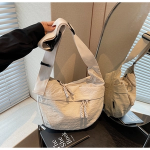 Detailed close-up of a cream crossbody bag with pleated texture and adjustable strap