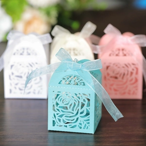 Detail of laser-cut rose hollow gift boxes with elegant ribbon bows for wedding favors