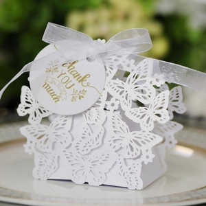 Detailed laser-cut white butterfly favor box with gold-stamped Thank You tag and silk ribbon