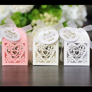Detailed laser-cut heart favor boxes in pink and white with ribbons and thank you tags