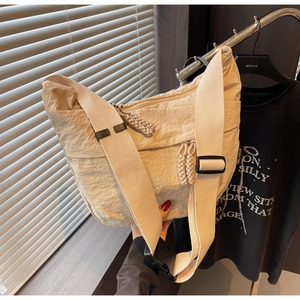 Detail of minimalist beige nylon crossbody bag with textured fabric and woven zipper pull