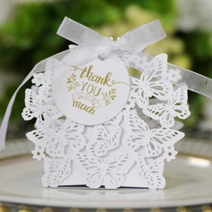 Macro detail of white laser-cut butterfly wedding favor box with thank you tag and ribbon