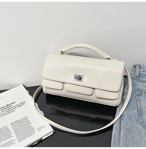 Detail of cream square handbag showing silver twist lock and decorative front flap pockets