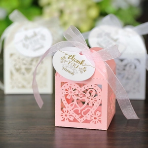 Close-up of laser-cut heart pattern on pink gift boxes with satin ribbons and thank you tags