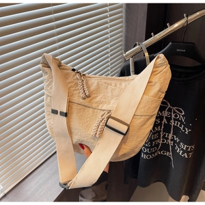 Detail of off-white nylon dumpling bag featuring pleat texture and adjustable wide strap